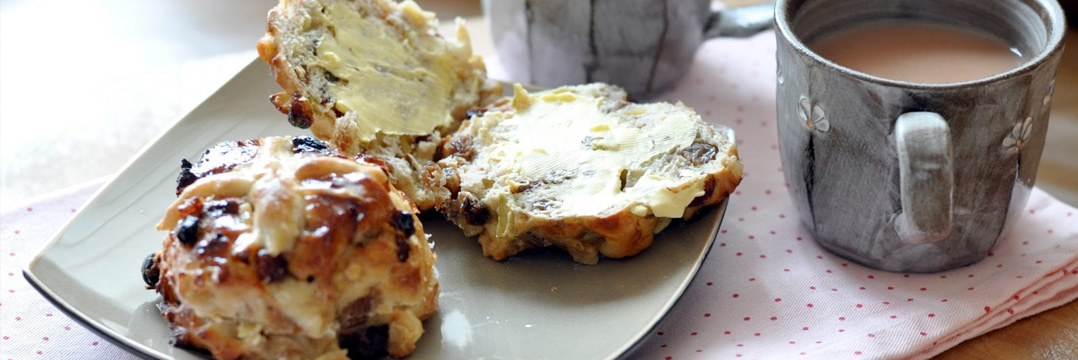 新鲜的十字面包和大杯茶